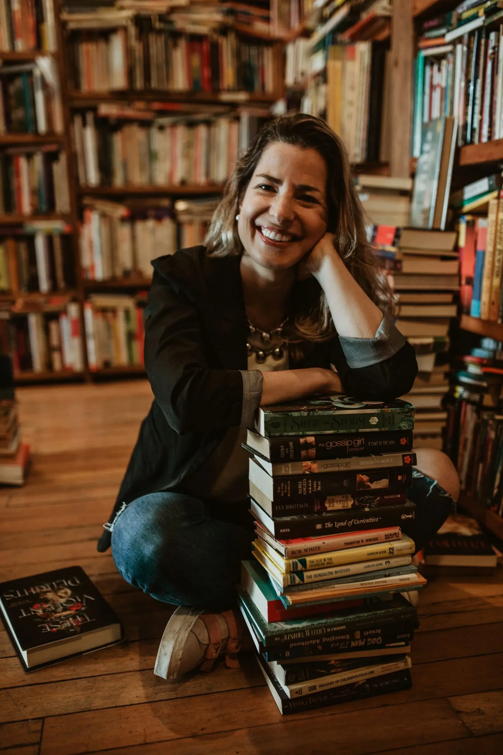 Isabel com livross Isabel arruda sentada apoida em uma pilha de livros