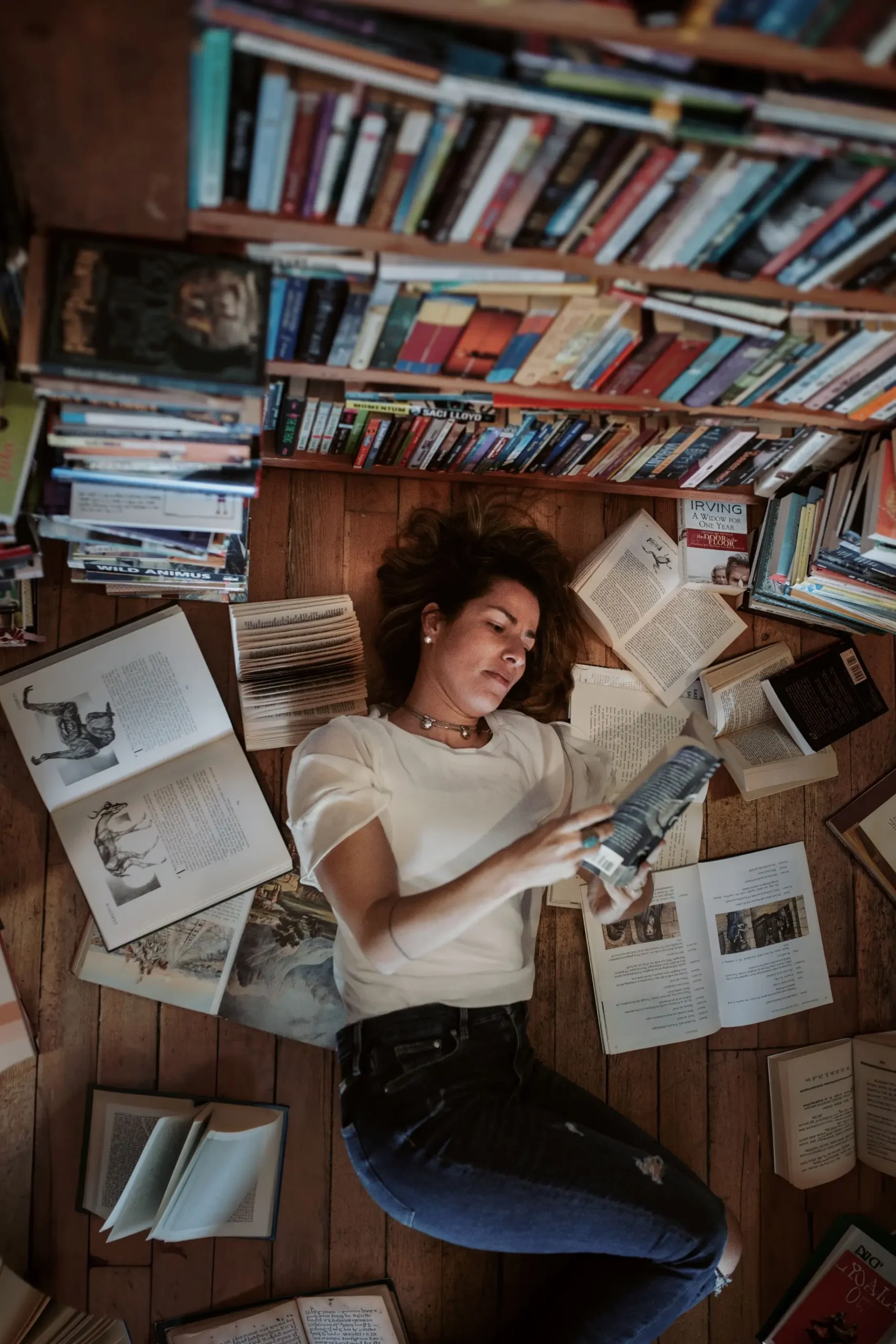 Isabel lendo livro no chão de uma biblioteca