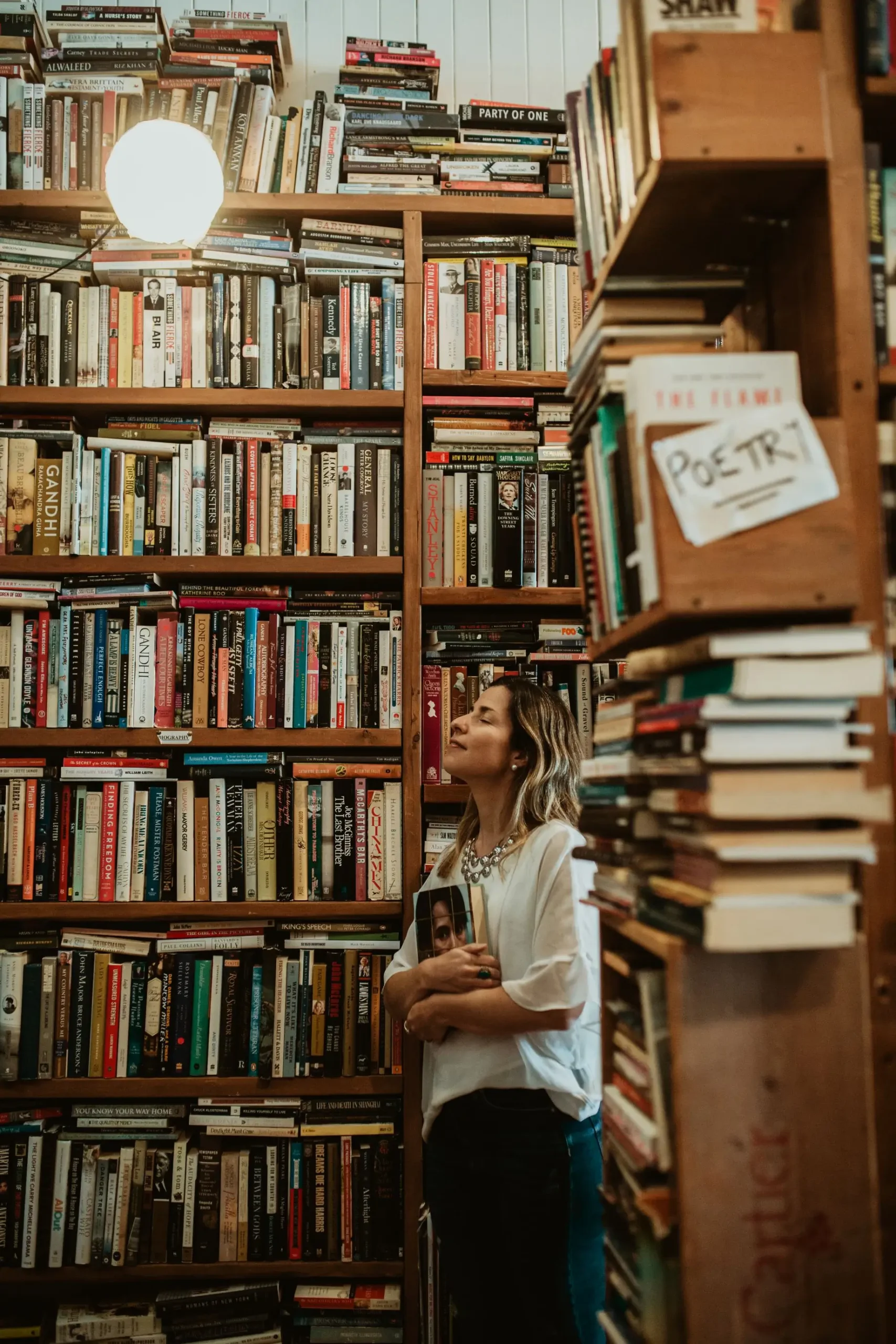 Bel na bibliote ca segurando um livro Isabel Arruda escritora lendo um livro na biblioteca